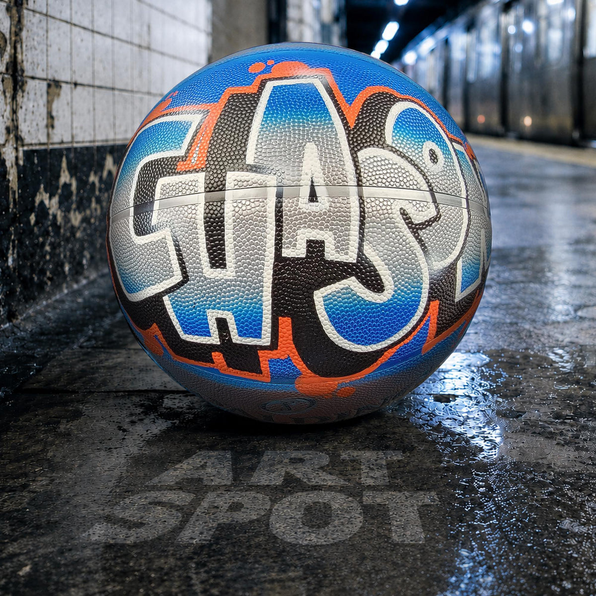 A basketball with graffiti text on it, resting on a wet surface.