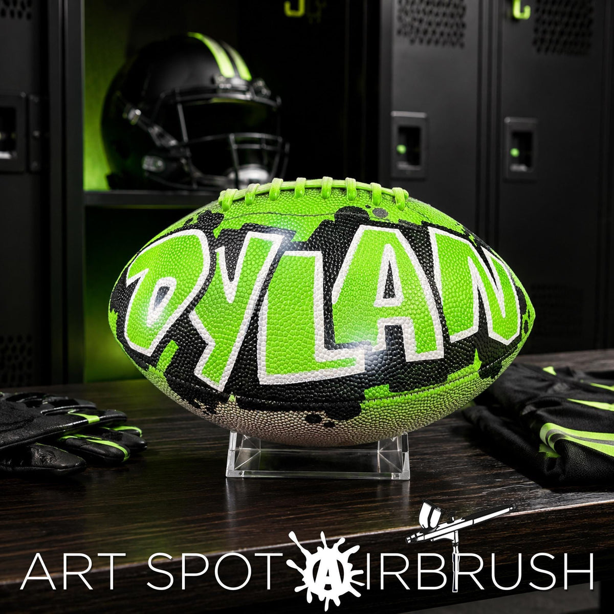A neon green and black personalized custom football with the name "Dylan" written on it, displayed on a wooden surface in a locker room setting.