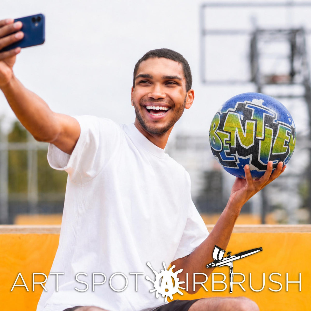 A man is taking a selfie with a blue and green sports ball, smiling and holding it up to his face.