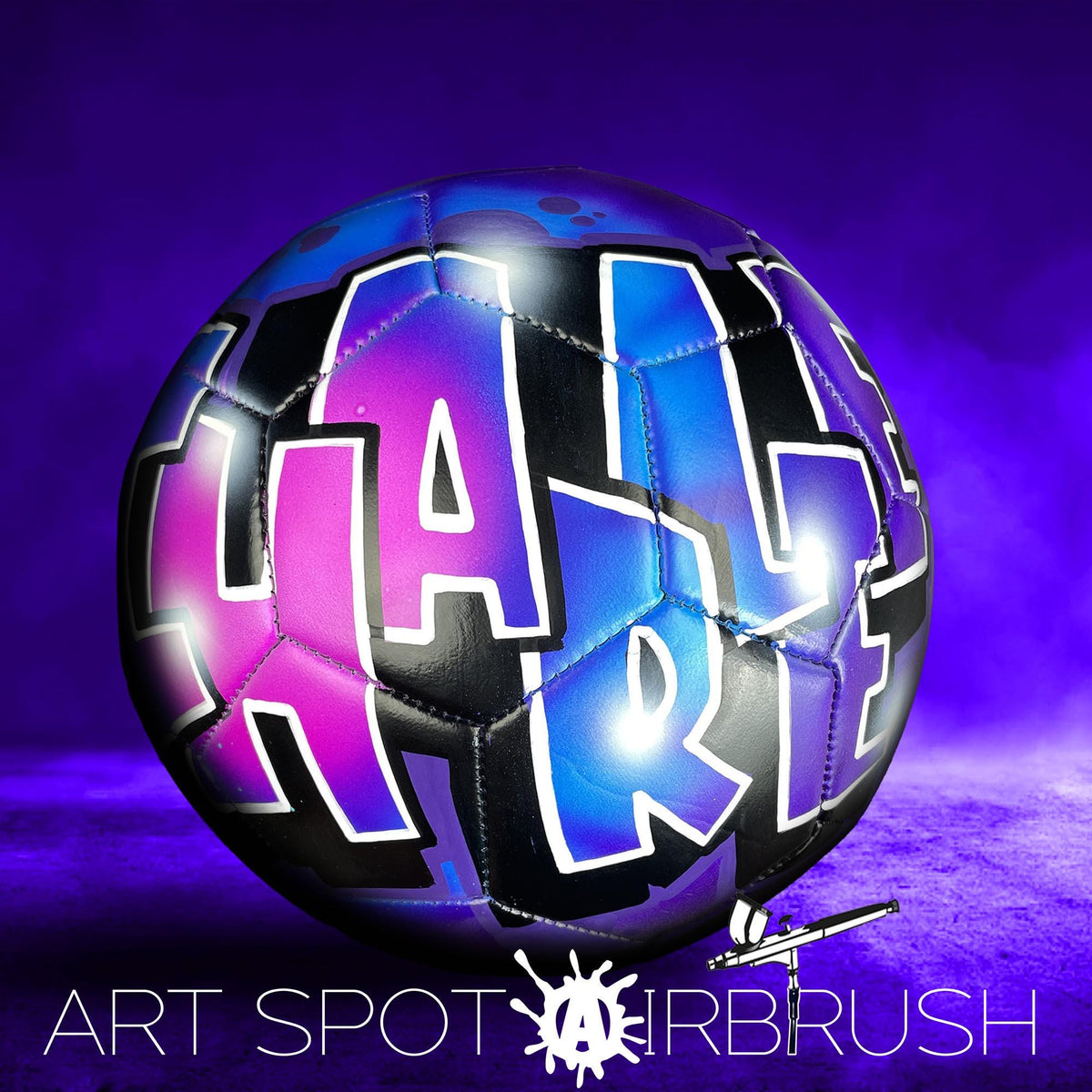 A colorful soccer ball with the word "HARF" painted on it, set against a purple background.
