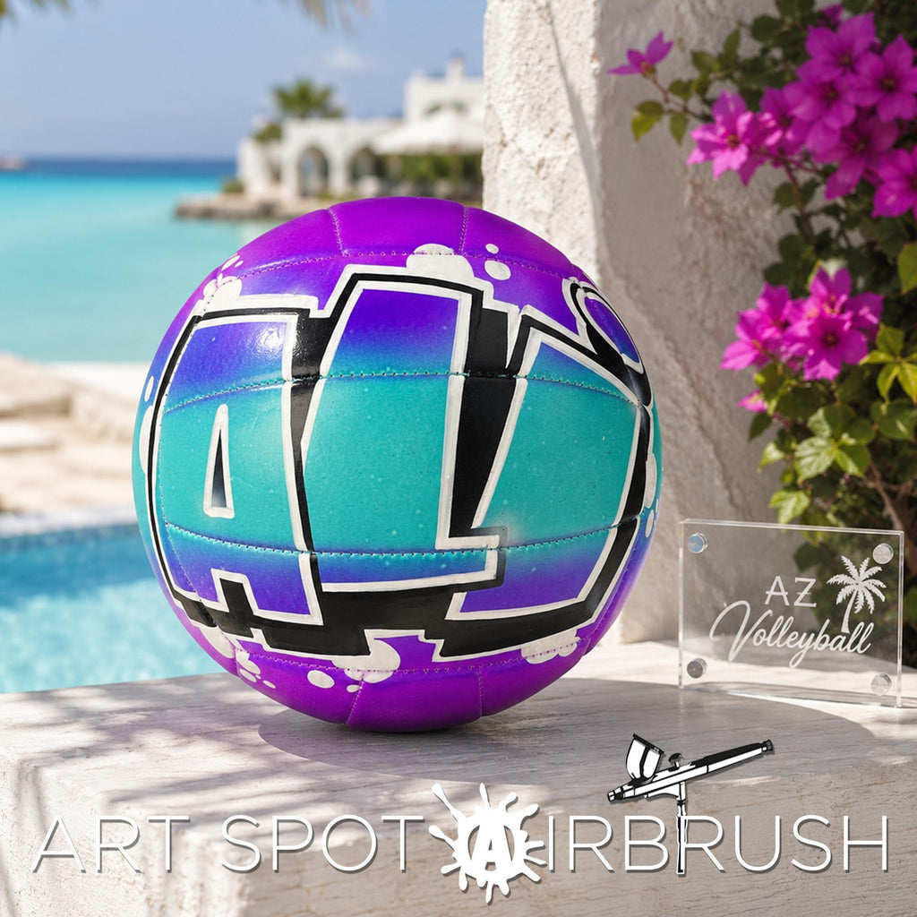 A purple and teal custom volleyball personalized with the word "ALI" painted on it, placed on a ledge next to a sign that says "AZ Volleyball". The background features a beach and palm trees.