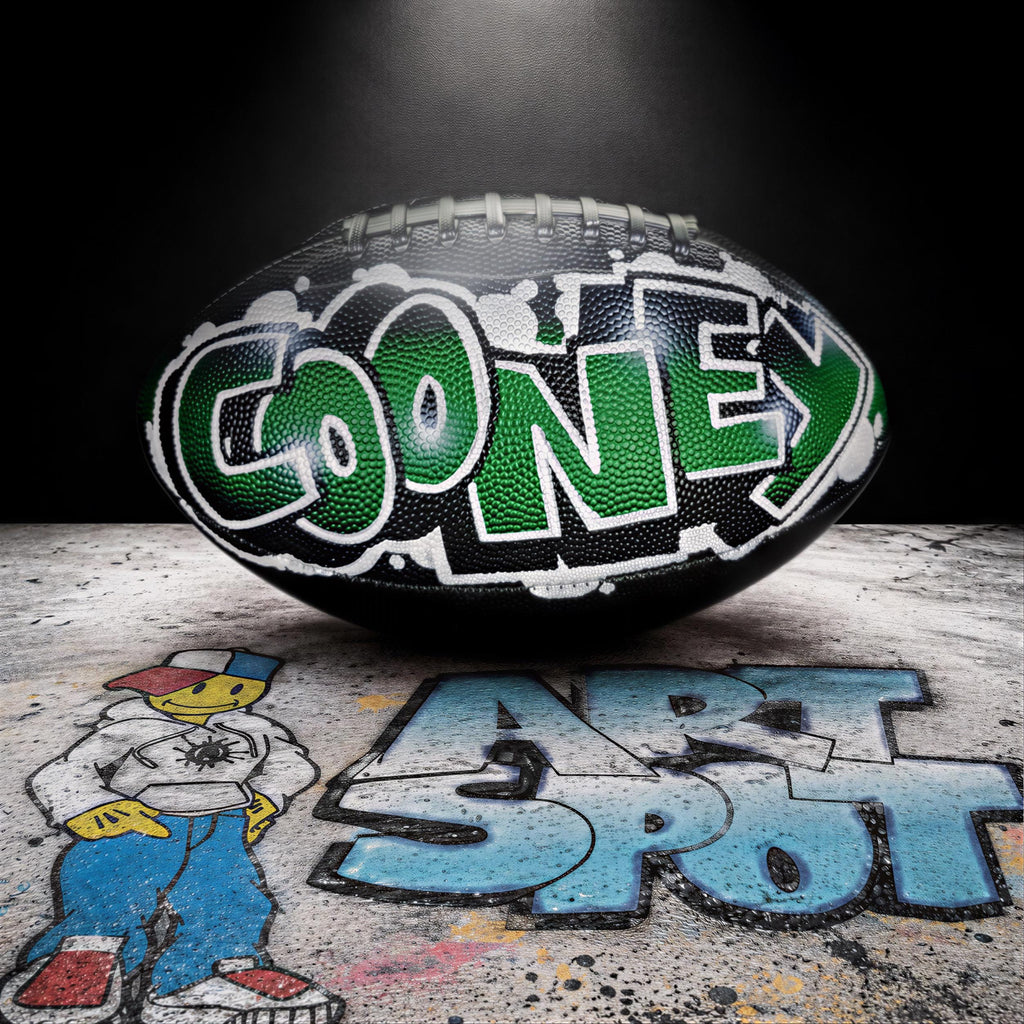 a football with the word "Cooney" written on it, placed on a surface with graffiti.