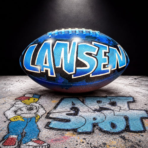 A blue and black football with the name "Lansen" written on it, placed on a surface with graffiti-style text.