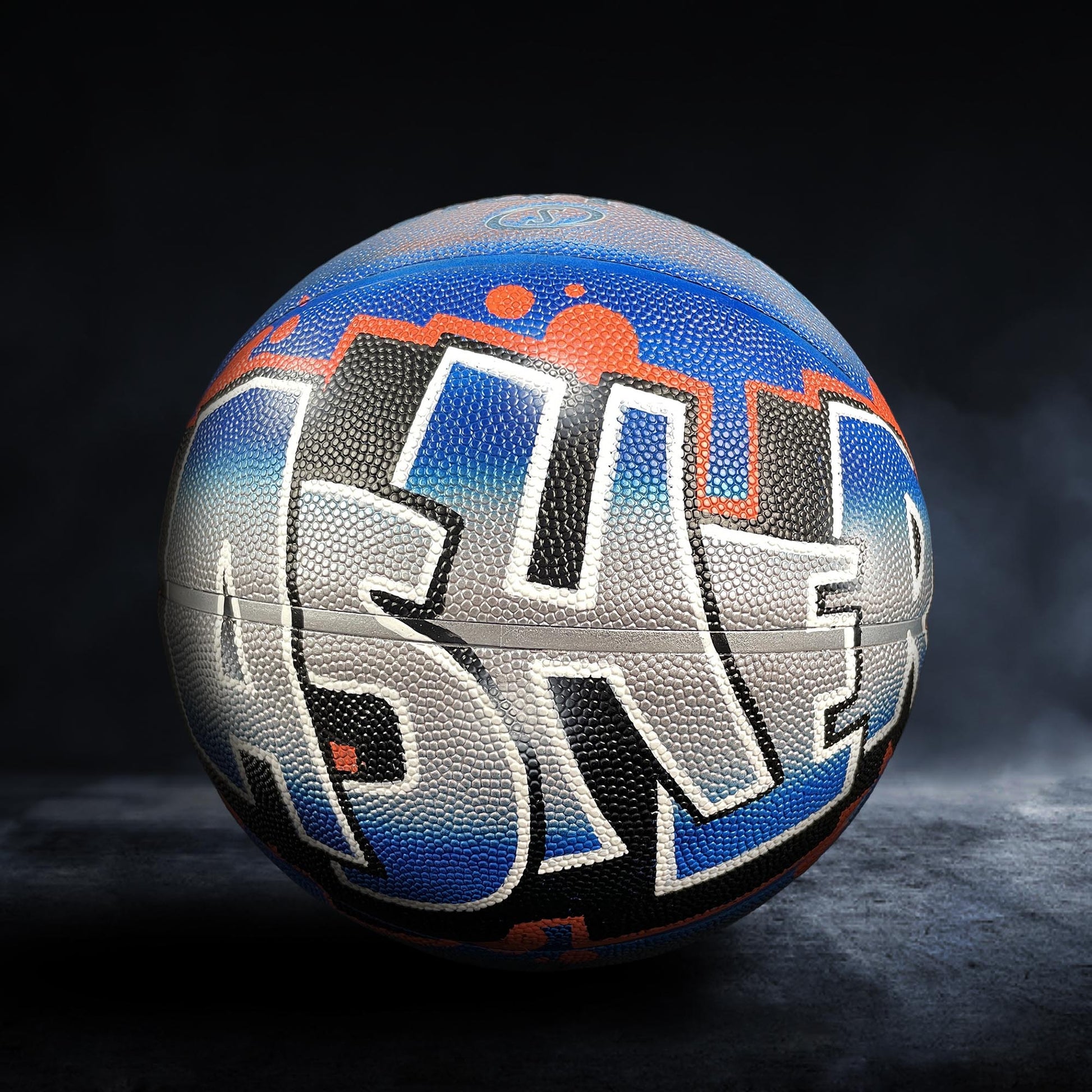 A basketball with graffiti writing on it, specifically the word "ASH" in large letters.