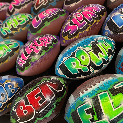 A collection of colorful footballs with various names painted on them.