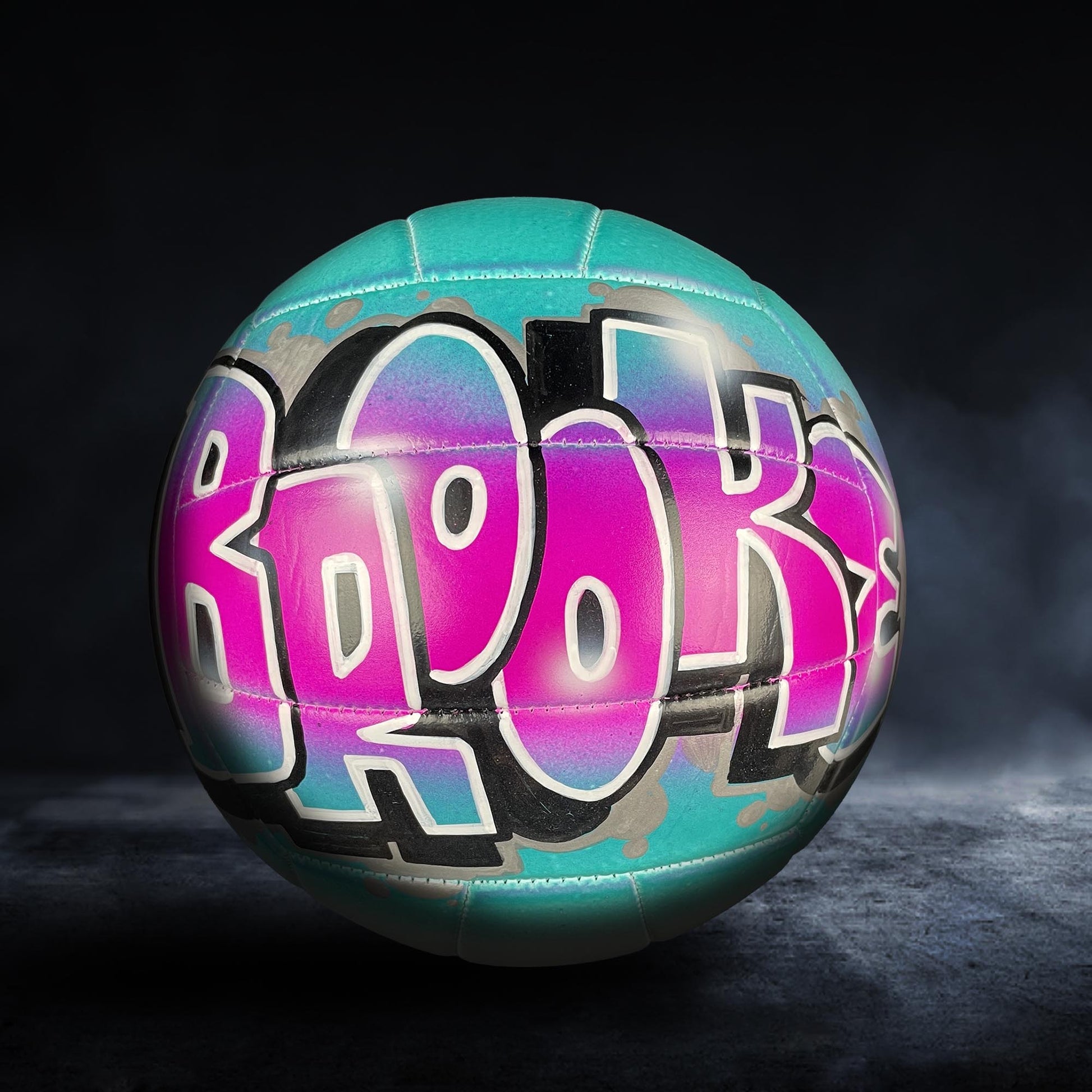 A colorful sports ball with the word "Brooks" painted on it, set against a dark background.