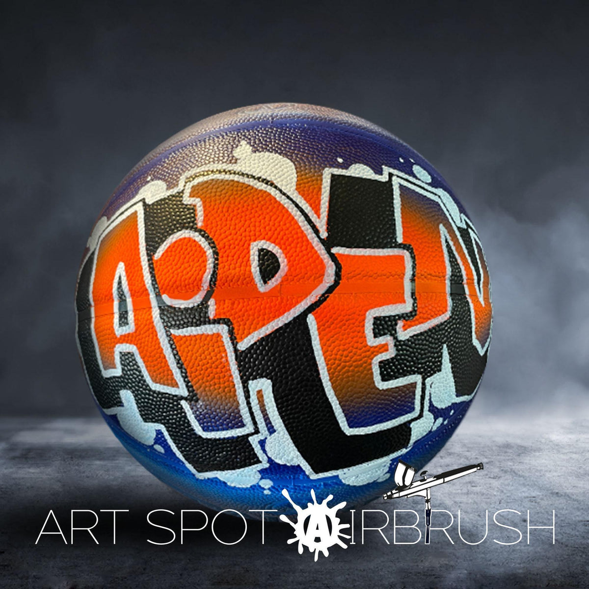 A basketball with the word "ART" painted on it, along with a spray paintbrush in the bottom right corner.