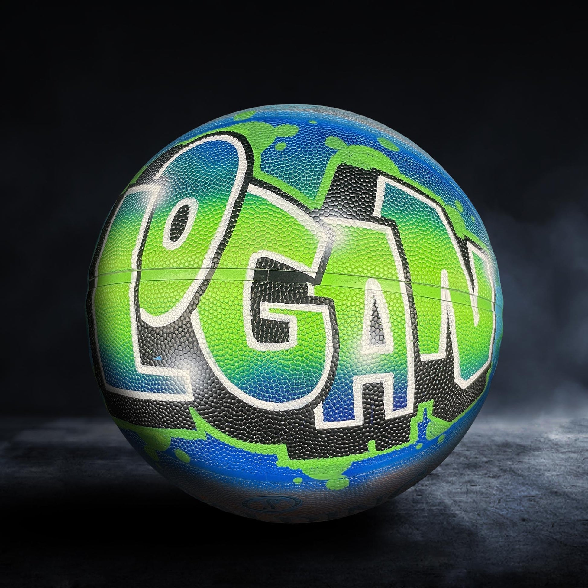 A basketball with the word "Logan" painted on it in a colorful, graffiti-style design.