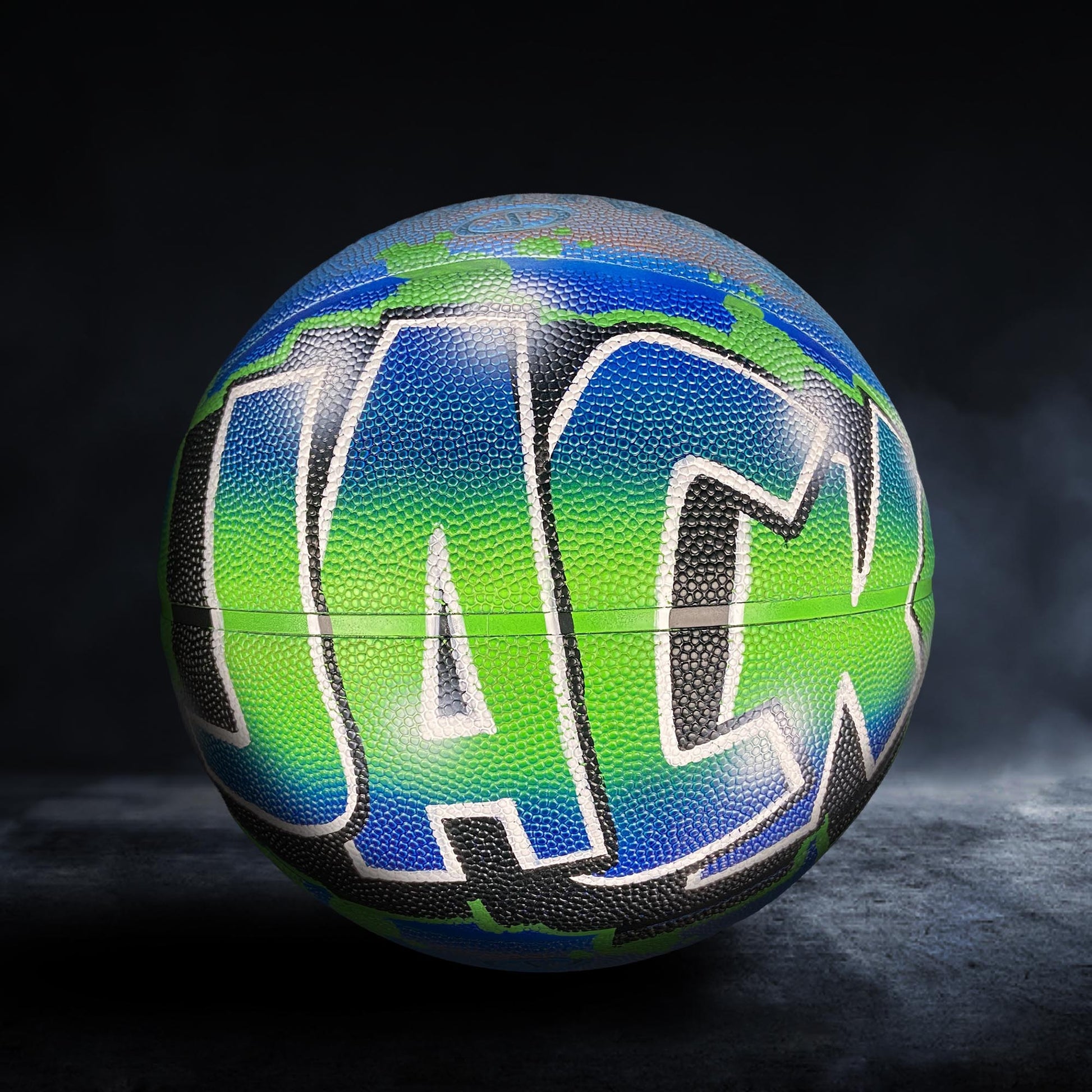 A colorful basketball with the word "JACK" painted on it, set against a dark background.