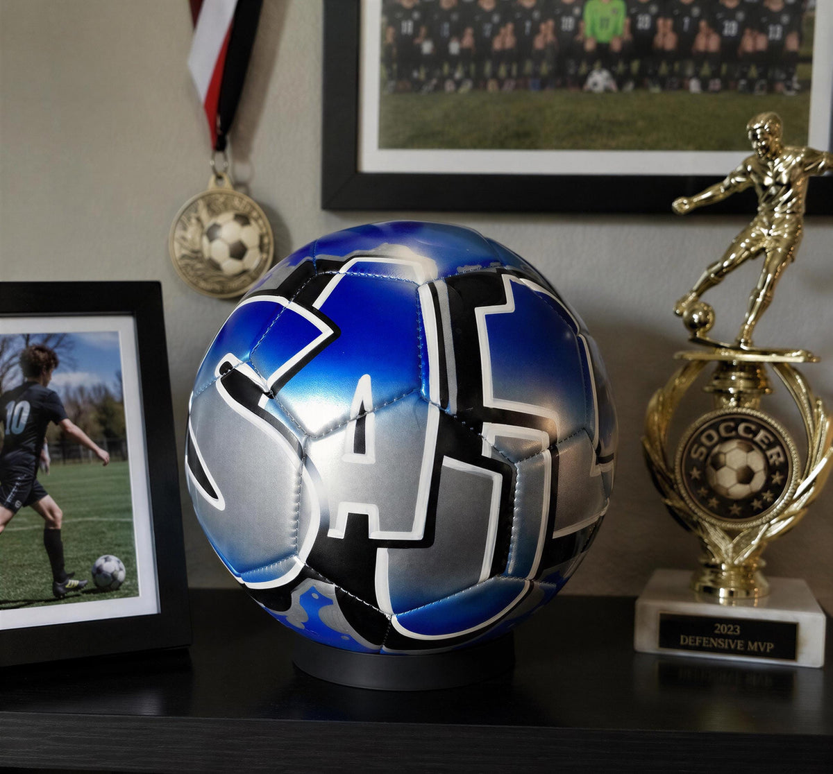 a soccer ball with a blue and silver design, a trophy, and a framed photo of a soccer player.