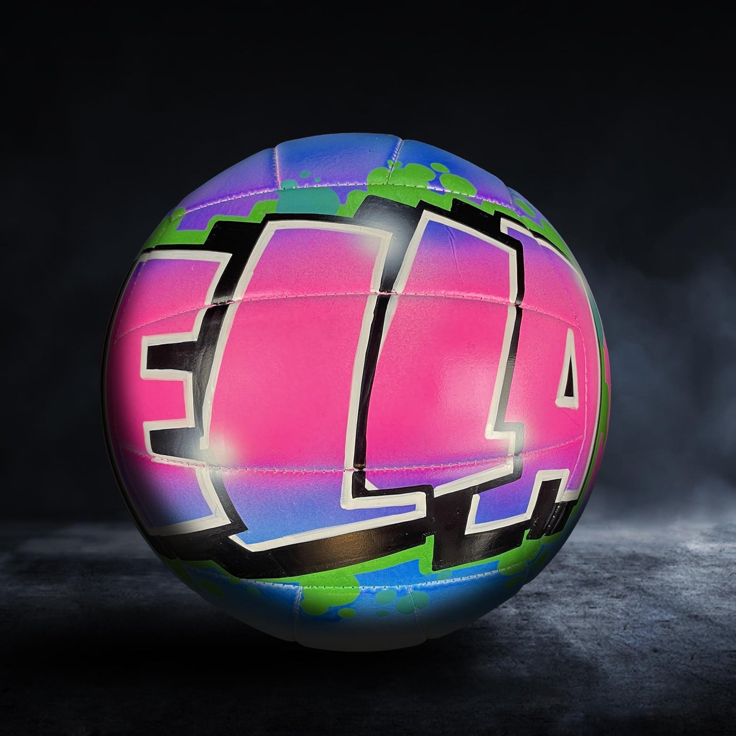 A colorful volleyball with the word "ELA" painted on it, set against a dark background.