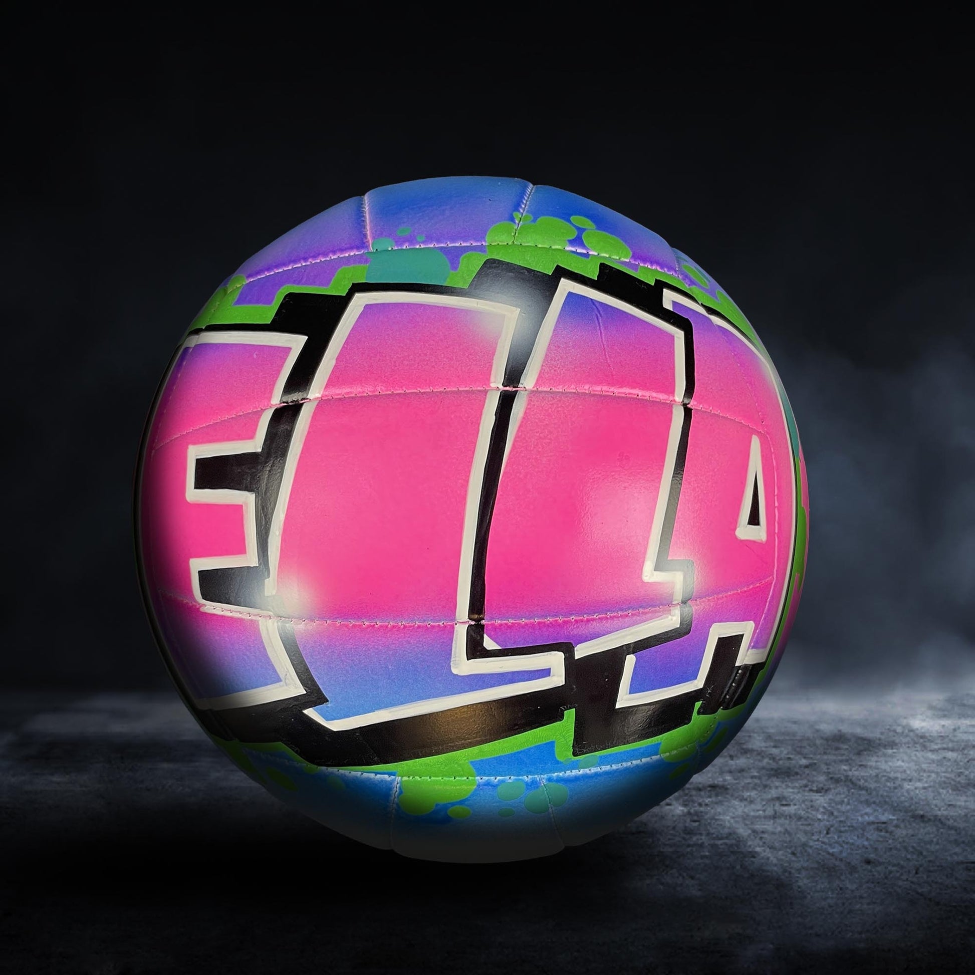 A colorful volleyball with the word "ELA" painted on it, set against a dark background.