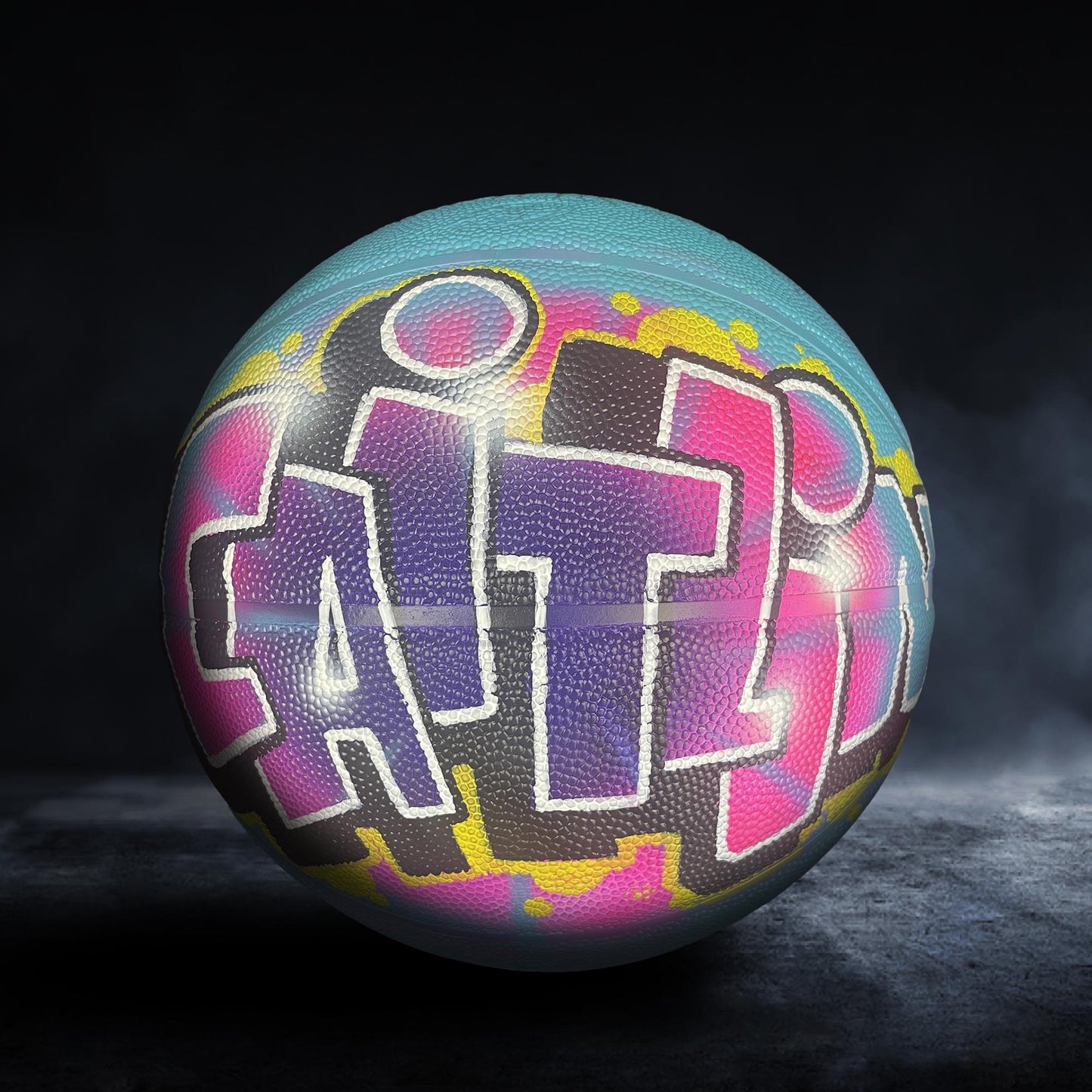 A colorful basketball with graffiti-style text on it, set against a dark background.