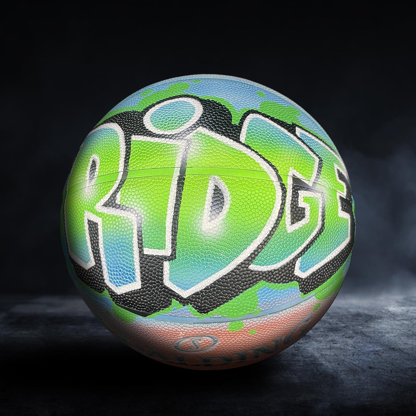 A colorful basketball with the word "RIDGE" painted on it, set against a dark background.