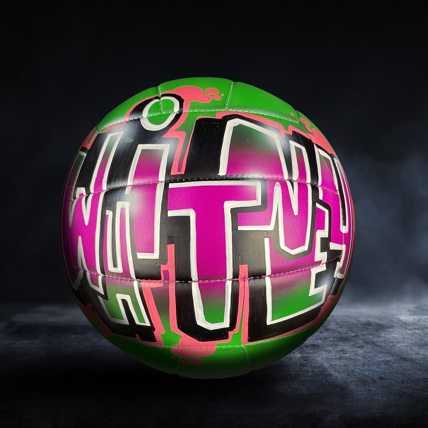 A colorful soccer ball with graffiti-style text on it, set against a dark background.