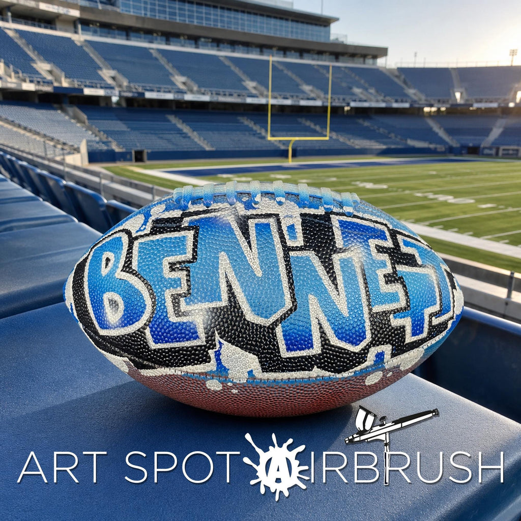 A personalized custom football with the name "BENNETT" written on it, placed on a blue surface in a stadium.