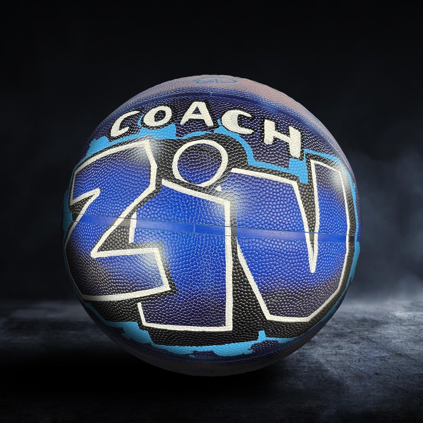 A basketball with the word "COACH" written on it in white letters.