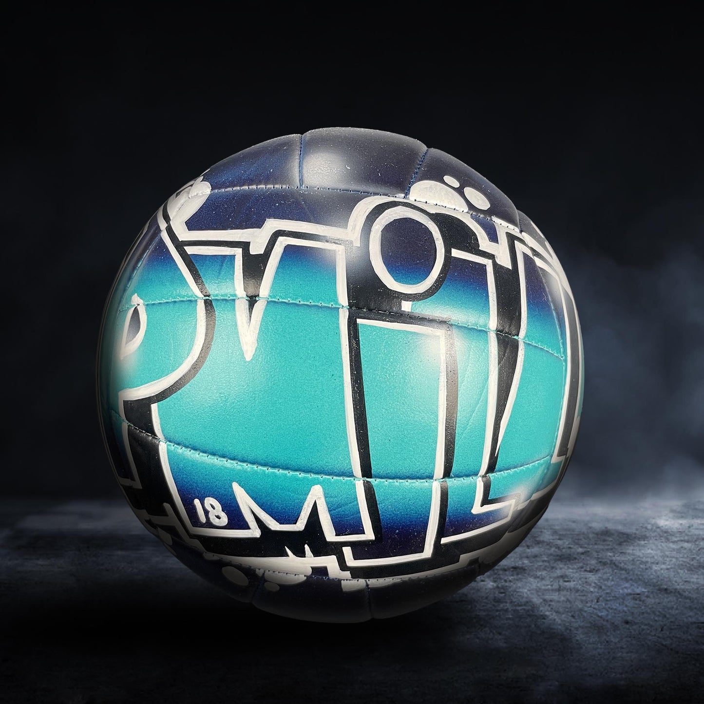 A soccer ball with a colorful, graffiti-style design on it, featuring the letters "PM" in a stylized font.