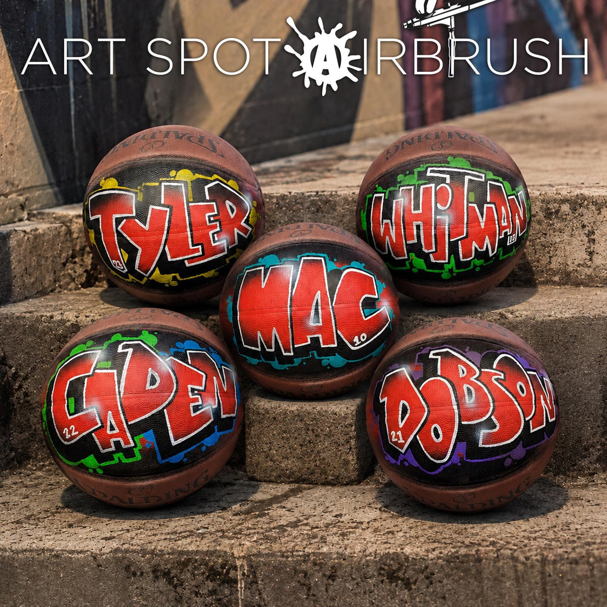 A group of five basketballs with personalized names painted on them, sitting on a set of concrete steps.