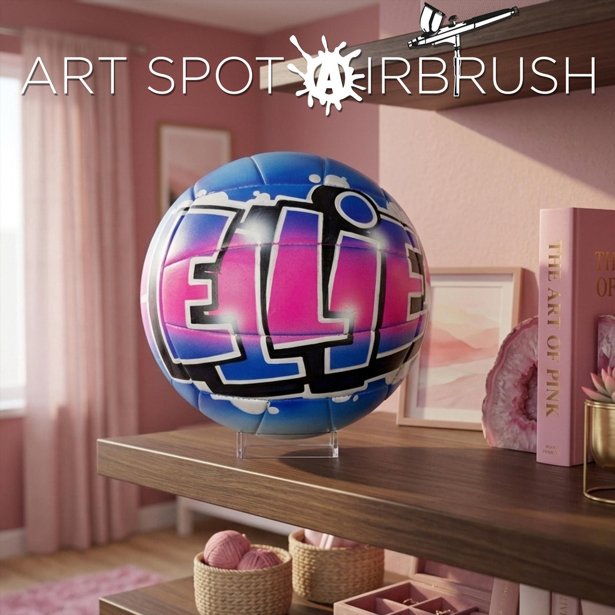 a custom volleyball personalized with the name "ELLIE" painted on it, displayed on a shelf in a pink-painted room.