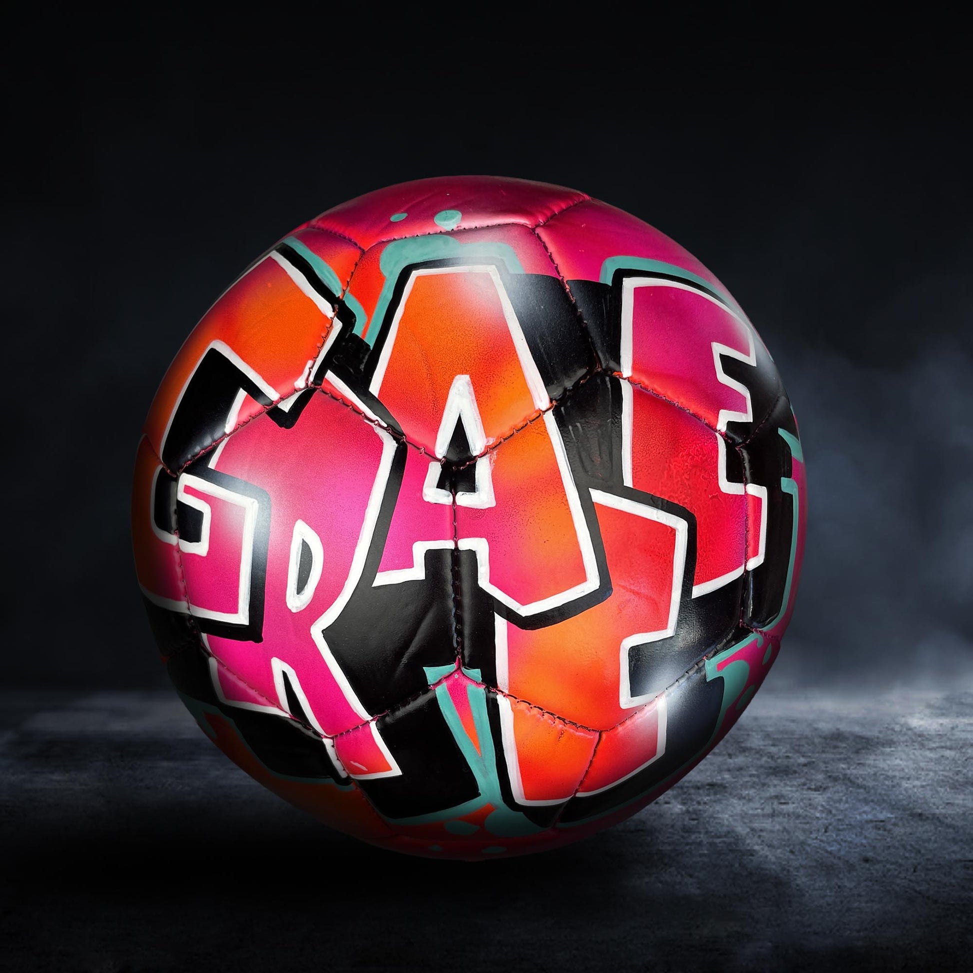 A colorful soccer ball with graffiti-style lettering on it, set against a dark background.