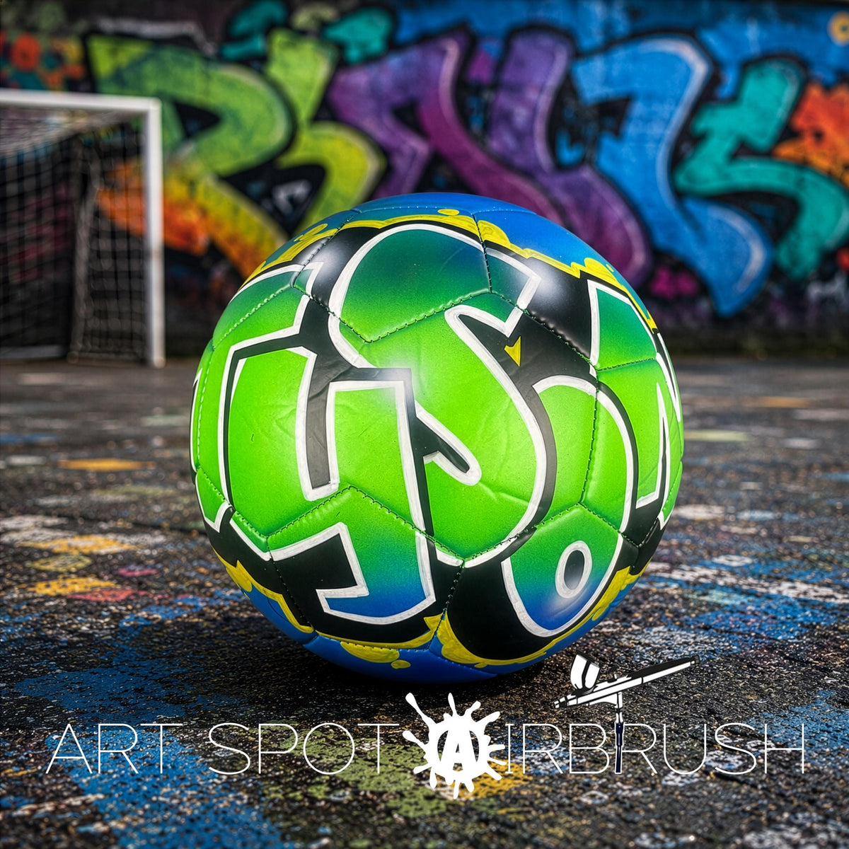 A soccer ball with colorful graffiti on it, placed on a surface with a graffiti-covered wall in the background.