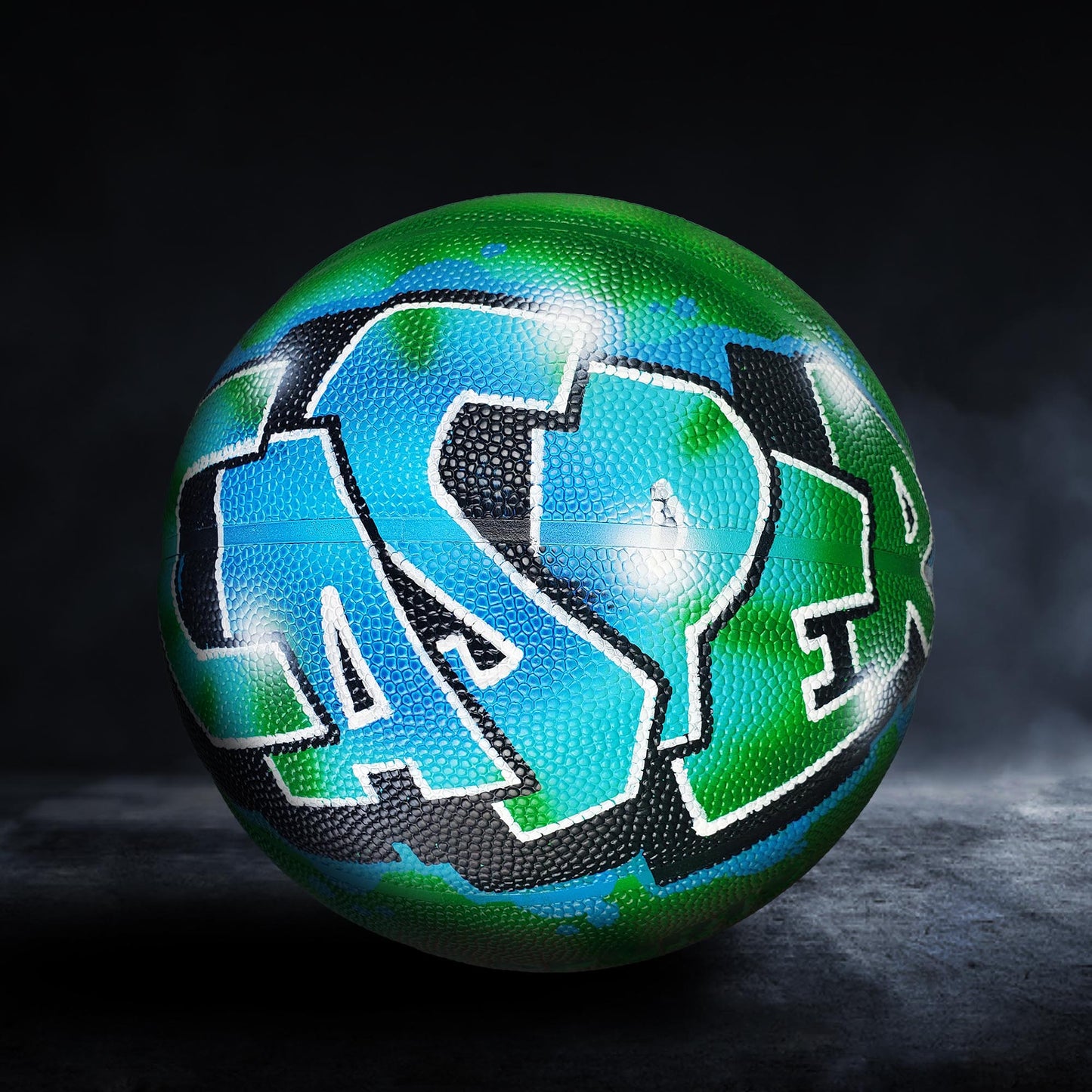 A basketball with a colorful, graffiti-style design on it, featuring the letters "CAS" in blue and green colors.
