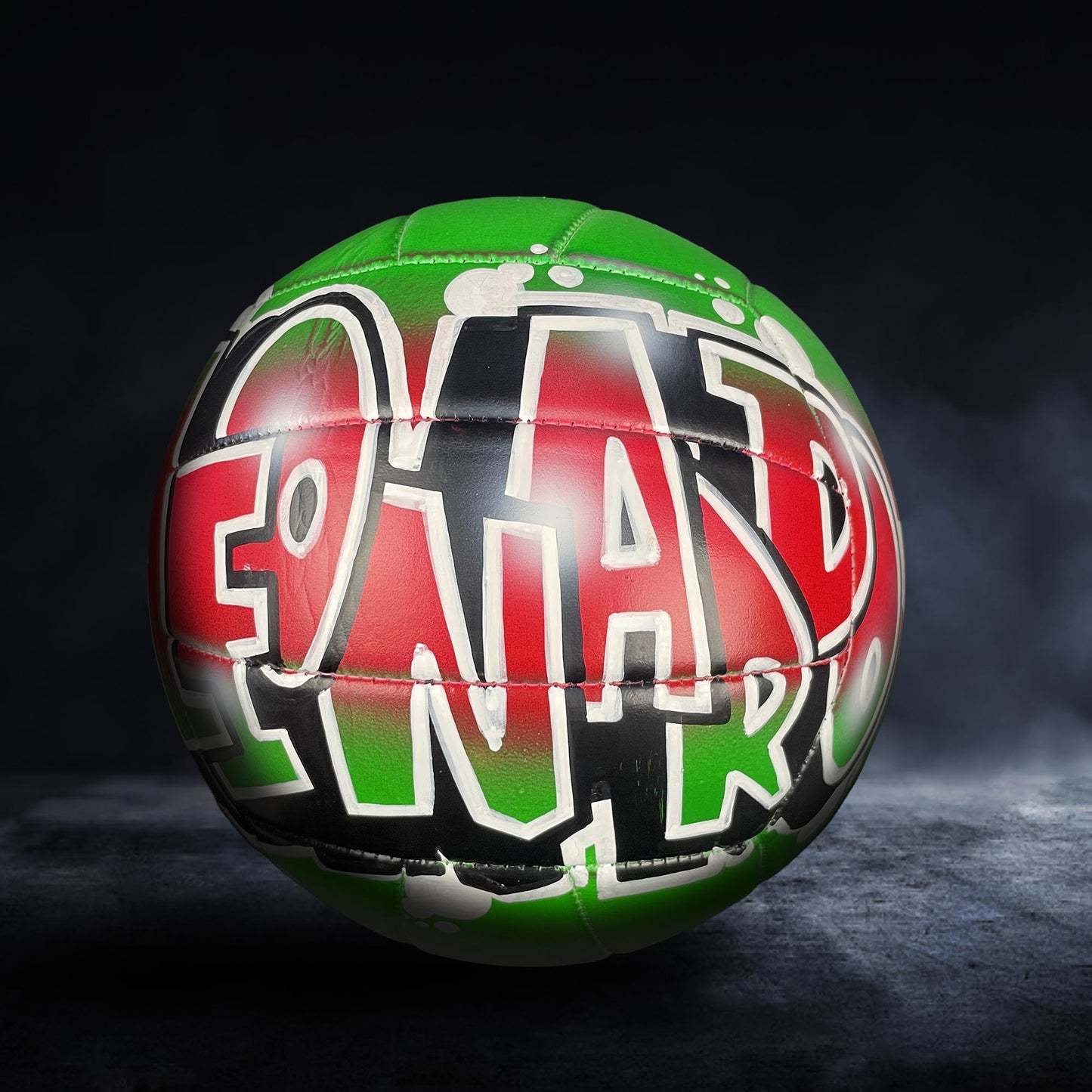 A colorful soccer ball with the word "FOOTBALL" painted on it, set against a dark background.