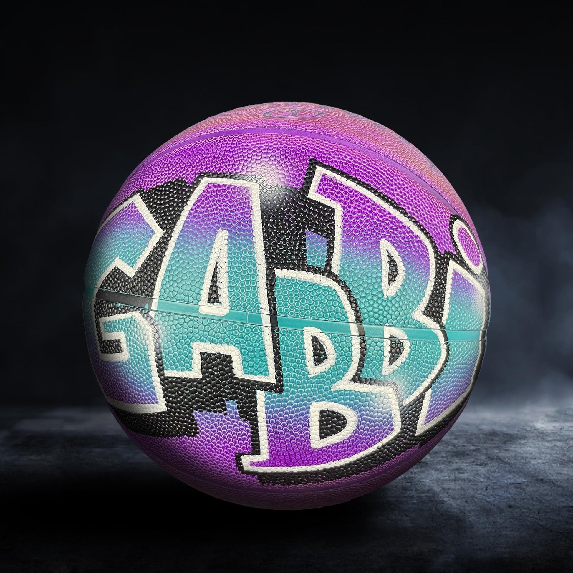 A colorful basketball with the word "GAB" painted on it, set against a dark background.
