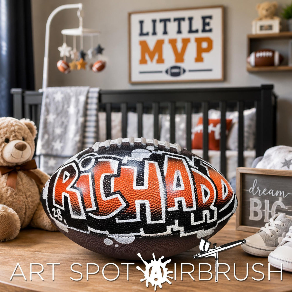 A personalized football with the name "RICHARD" written on it, along with a teddy bear and other sports memorabilia, is displayed on a wooden surface in a bedroom setting.
