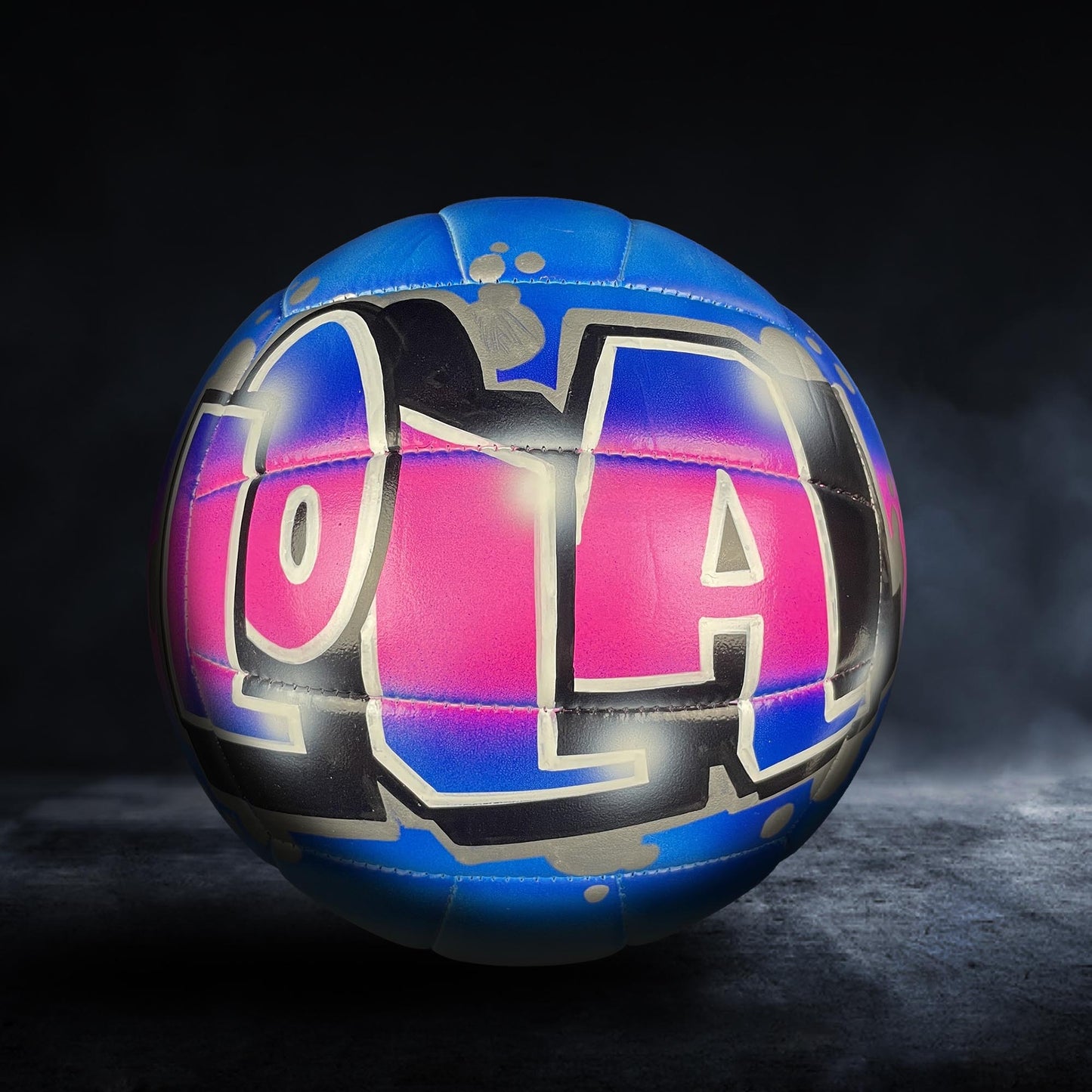 A colorful volleyball with the word "LOL" painted on it, set against a dark background.