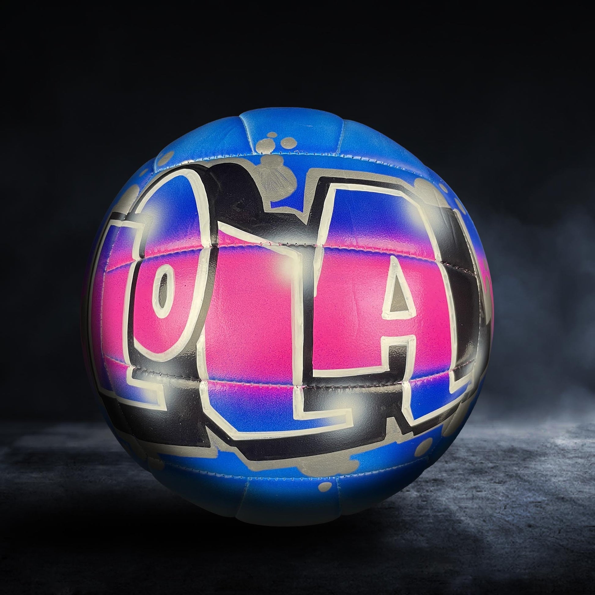 A colorful volleyball with the word "LOL" painted on it, set against a dark background.