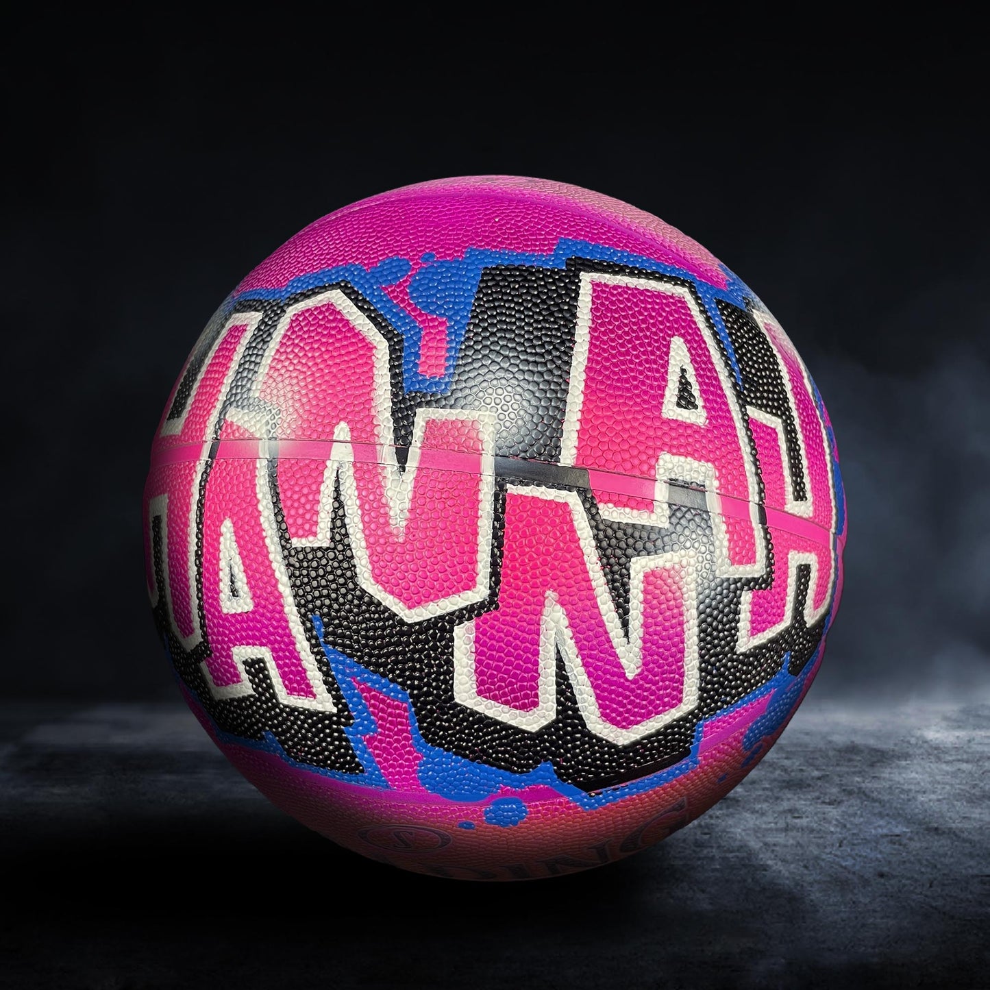 A colorful basketball with the name "Hannah" painted on it in pink and black.