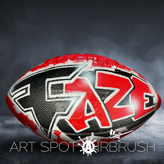 A football with a red and black design on it, placed on a dark background.